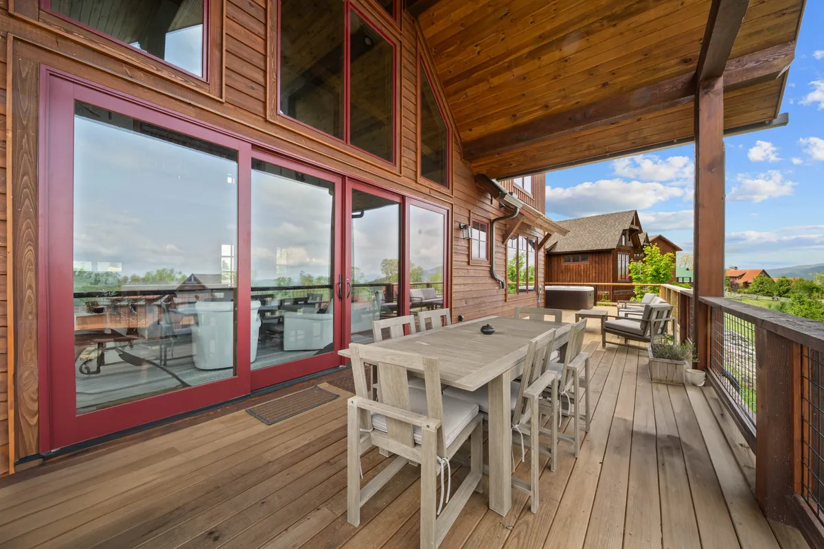This image displays a dining table positioned to take full advantage of large windows that frame a breathtaking scenic mountain view. The scene suggests opportunities for enjoying meals, drinks, and company while admiring the ever-changing light over the landscape, reinforcing the lodge’s connection to its natural setting.